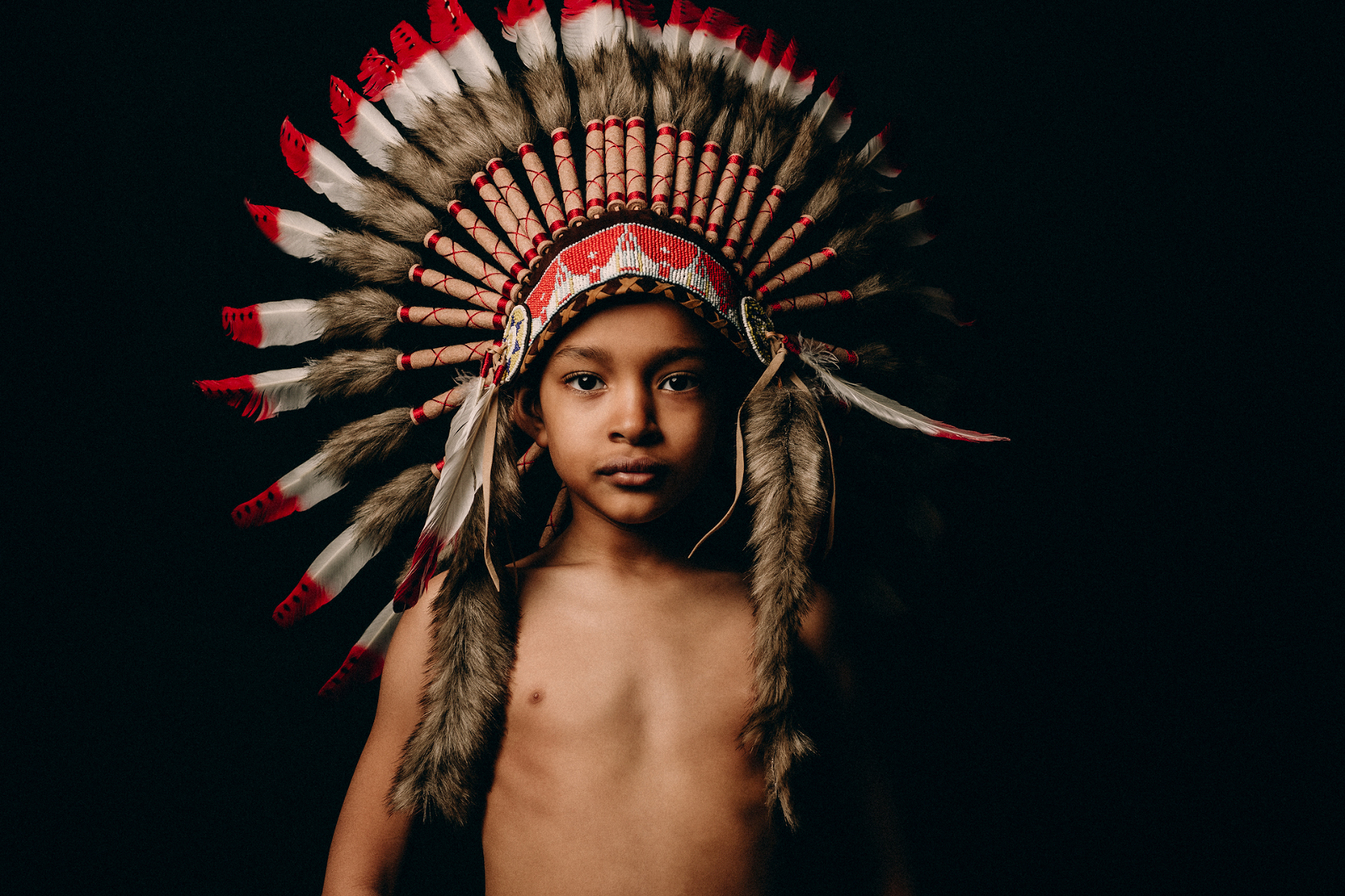 Portrait of a young boy wearing an Indian headdress
