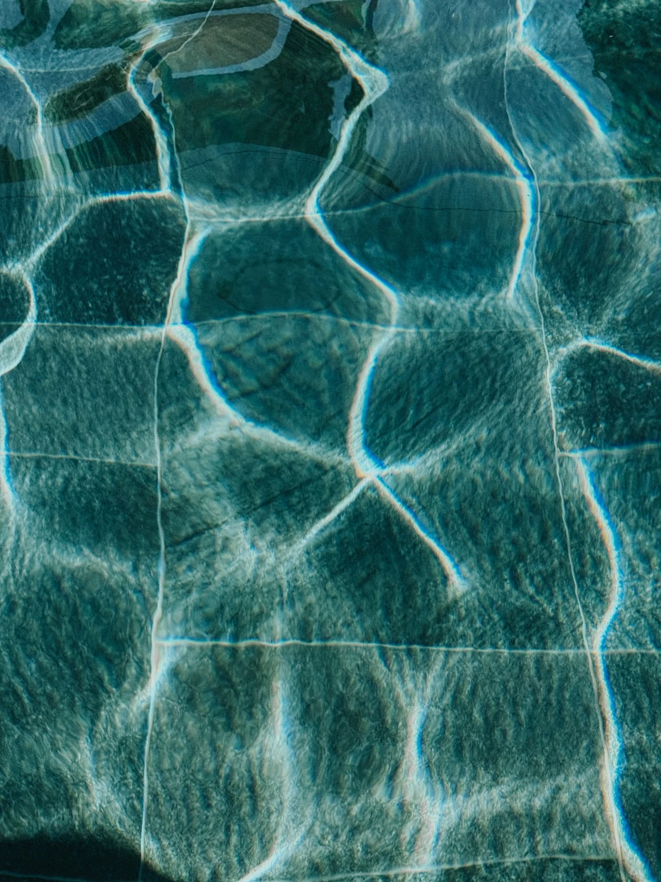Rippling turquoise swimming-pool water patterned with sunlight in Samos.